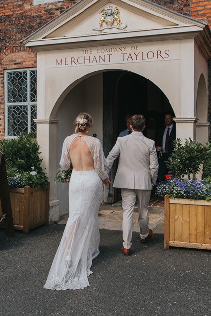 The arrival of a wedding couple, the couple are heading inside the building with the groom leading the way holding the brides hand