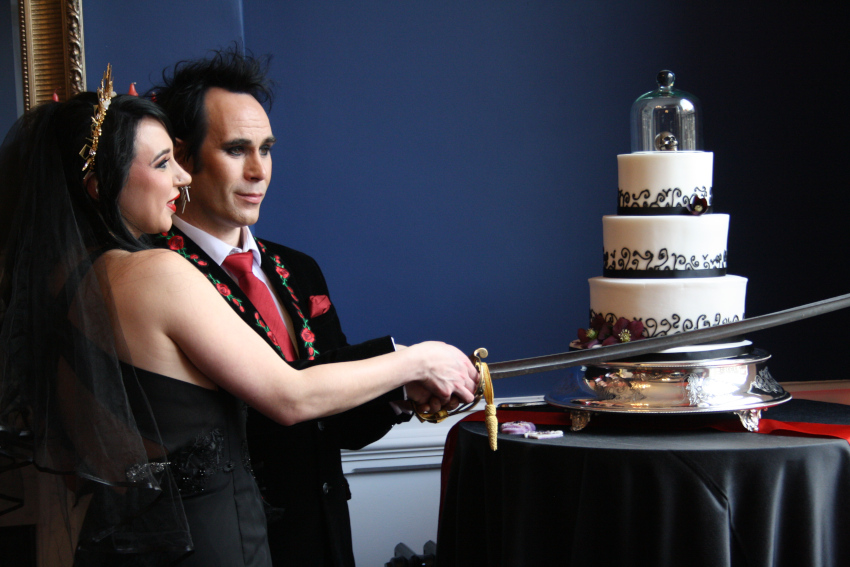 Bride and groom cut wedding cake with a sword