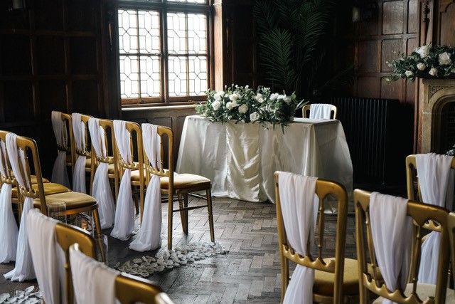 Impossible York wedding venue ceremony room. Photo taken from within the seating area, looking towards the front table, showcasing the ornate windows and parquet flooring