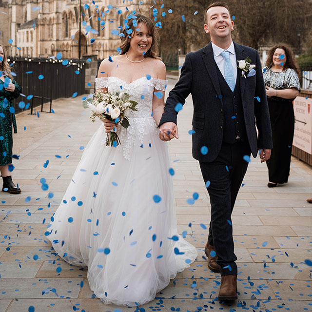 York Minster Refrectory wedding venue, couple walking under confetti after just being married