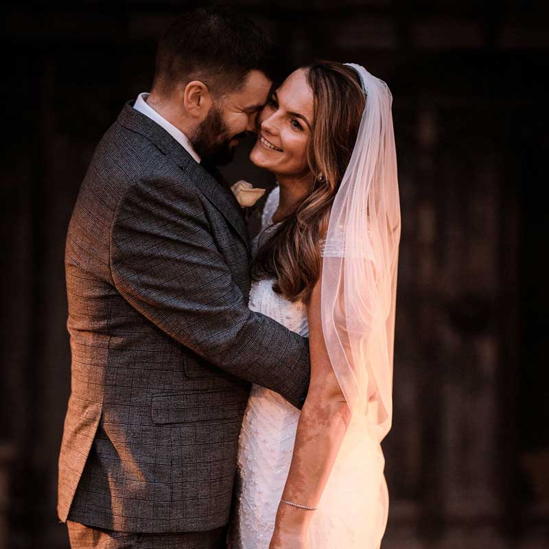 A bridge and groom embrace whilst smiling